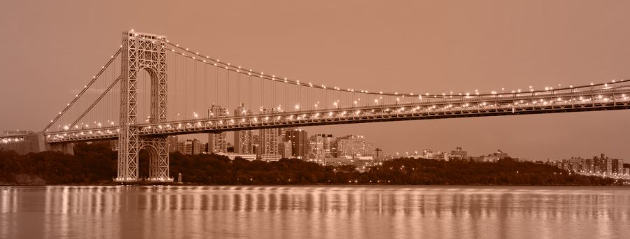 George Washington Bridge at dusk with city skyline.